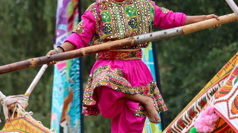 Tightrope walker in gardens at Rainham Hall, brightly dressed costume